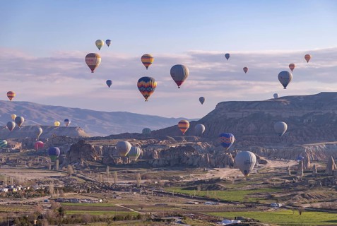 A picture of colorful hot air balloons flying over the landscape of Goreme Historical National Park