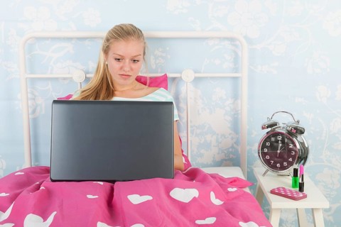Teen girl with laptop in bed