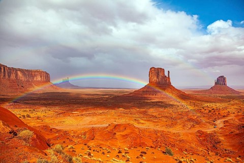 The bright rainbow all over the sky. Monument Valley is a unique geological formation in Arizona