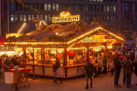 Sausage roasting stand with many people at the Bremen Christmas market at dusk, Bremen, Germany