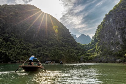Boats in the river under bright sunlight and green mountains, rowing boats for tourists in Halong