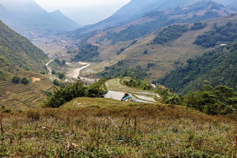 An impressive landscape with green valleys, hills and a meandering river, farms in the rice paddies