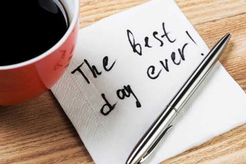 Coffee cup pen and napkin with words on wooden table