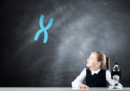 Little girl scientist with microscope on chalkboard background with x chromosome. Research and