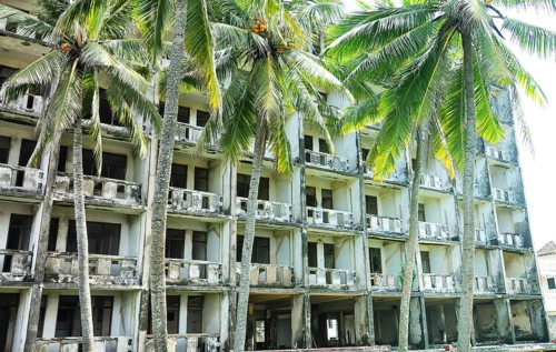 Abandoned hotel in coastal recreation area in Southeast Asia. Palm trees and failed otel business