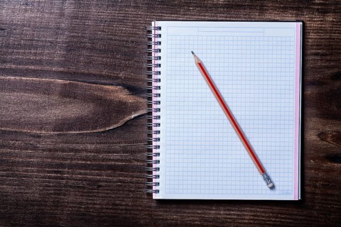 Pencil and checked copybook on wooden board education concept