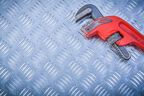 Metal pipe wrench on channeled metallic sheet maintenance concept