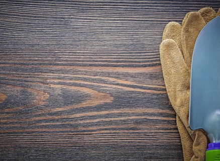 Metal shovel leather safety gloves on wooden board copy space gardening concept