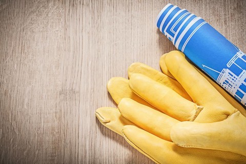Leather safety gloves blue construction plans on wooden board top view