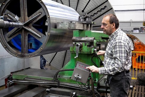 An older employee in the metal industry works on a CNC milling machine, Senior, 65, years,
