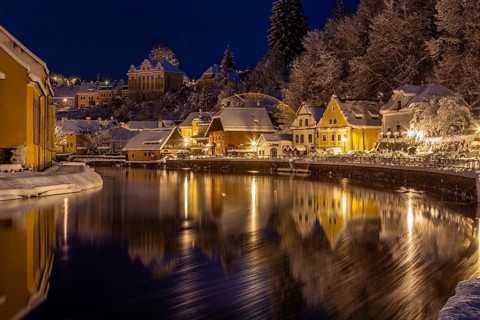 Winter view of Cesky Krumlov, picturesque houses under the castle with snow-covered roofs. Narrow