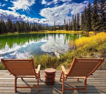 Two wooden deckchairs for tourists on ashore shallow round lake. Autumn day in Jasper National Park