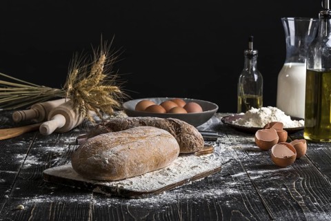 Beautiful still life with different kinds of bread, grain, flour on weight, ears of wheat, pitcher
