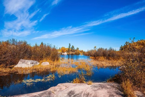 Old Pinawa Dam Provincial Heritage Park. Warm day. Yellow autumn grass is reflected in the Winnipeg