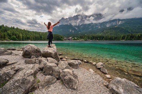 Zugspitze Peak top of Germany Alps mountain range and Eibsee Lake with woman tourist, Garmisch