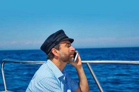 Captain cap sailor man talking mobile phone in boat sailng in the ocean sea