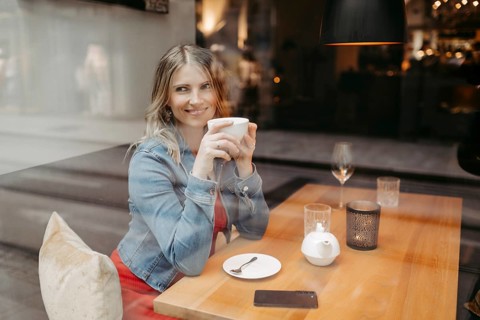 Blonde, attractive woman, 40+, sitting in a coffee house by the window