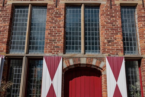 Red brick building with large mullioned windows and red and white shutters, Xanten, Lower Rhine,
