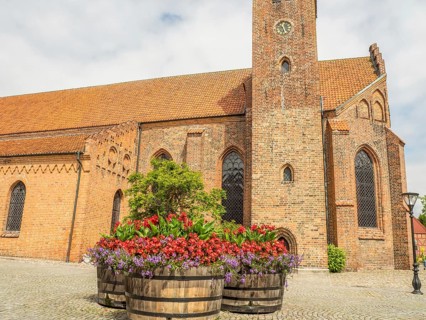 Church in the background with large flower pots in the foreground, historic brick walls, ystad,