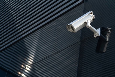 Photo of Modern CCTV camera on a wall. A blurred night cityscape background. Concept of
