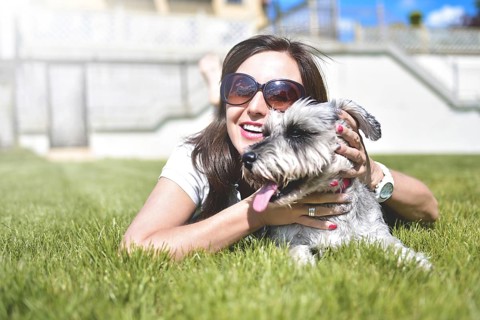 Pretty adult caucasian happy woman resting in the park on a sunny day with her beloved dog. Female