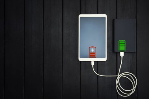 Power bank loads tablet PC, smartphone, isolated on wooden background. charging concept. free