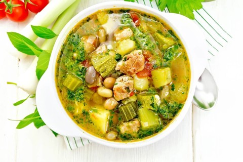 Soup with pisto sauce, pork fat, tomatoes, zucchini, beans, celery and leek in a bowl on a napkin