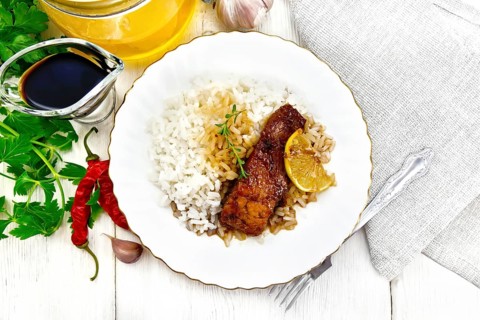 Pink salmon with honey, lemon juice and soy sauce, boiled rice, slice of lemon and sprig of thyme
