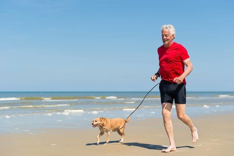 Senior runner with dog at the beach