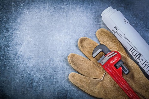 Monkey wrench protective gloves blueprints on scratched metallic background plumbing concept