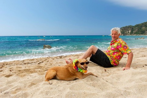 Relaxing elderly man with dog laying at the beach