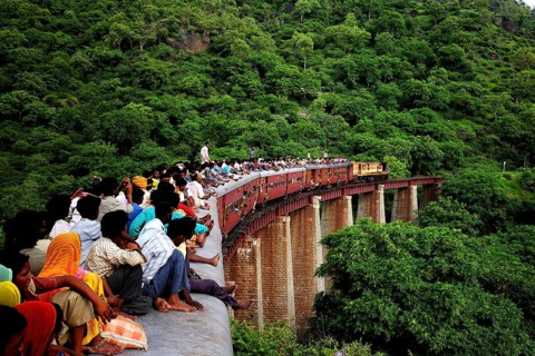 Commuters sitting on roof of train on bridge, Kamali Ghat, Rajasthan, India