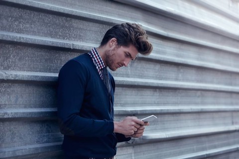 Young businessman texting smartphone phone on the street metal fence