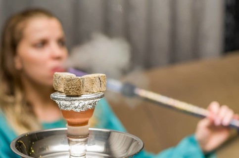 Woman in background blurred, smoking traditional Hookah (Narguile, Shisha, Chicha, Arguile),