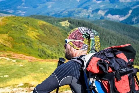 Man hiker on the trail hiking the mountain. A man sitting on a trail and looks at the beautiful