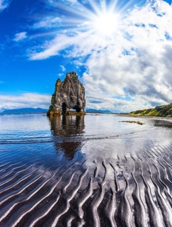 Pale northern sun of Iceland at sunset. The Basalt rock - Elephant Hvitsercur during an ocean