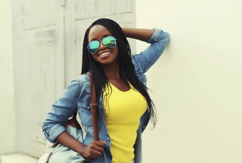 Portrait of happy stylish young african woman in casual clothing, glasses with dreadlocks, backpack