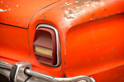 Old rusty red car with chrome bumper