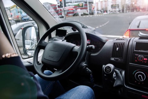 Inside a vehicle with a view of traffic and buildings through the windshield