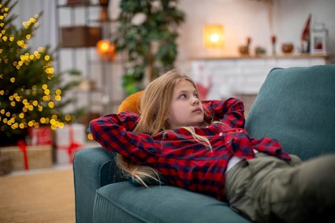 A young child lounges comfortably on a plush sofa, thoroughly enjoying the warm and cozy atmosphere