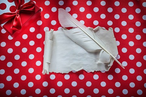 Present box vintage paper roll feather on polka-dot red tablecloth celebrations concept