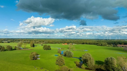 Aerial view of a beautiful green landscape with a small river flowing through. It is in the eastern