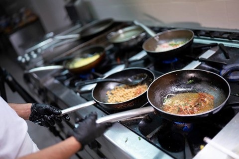 Chef cooking with various ingredients in pans on a stove
