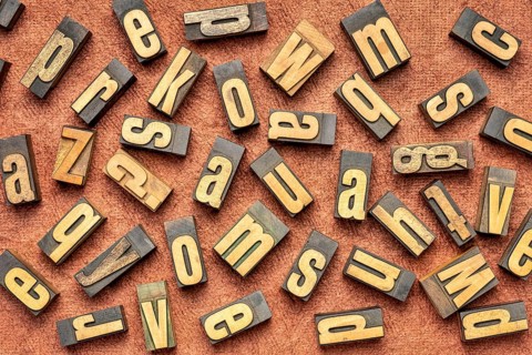 Random letters overhead background - vintage letterpress wood type (inverted image) against brown