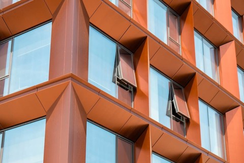 Modern office building exterior with glass facade on clear sky background. Transparent glass wall
