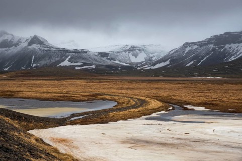Icelandic dramatic landscape with frozen lake and mountains covered in snow in winter Iceland