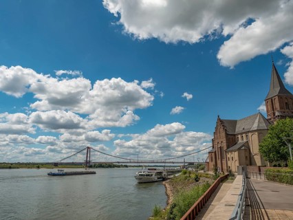 Historic church with a bridge and a ship on the river under a cloudy sky, emmerich, lower rhine,