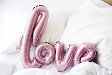 Large pink inflated letters LOVE on linens on the bed. The trend for Valentine's Day