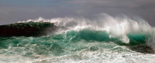 High wave piles up metres high in front of rolling over. Landscape format. High wave towers metres
