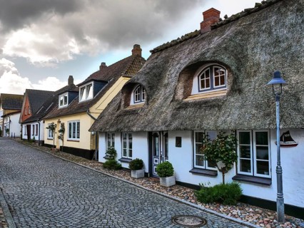Traditional houses with thatched roofs and cobblestone streets under a cloudy sky, maasholm,